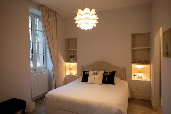 A bedroom with a bed, bedside lamps, a window with curtains, and a hanging light fixture. - Château de Quincey (Quincey)
