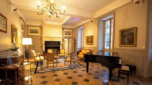 A grand room with a piano, a fireplace, and a chandelier.