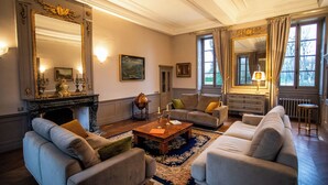 A spacious living room with a fireplace, large windows, and elegant furniture.