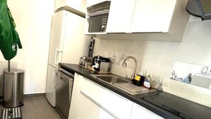 Una cocina moderna con armarios blancos, encimera negra y electrodomésticos de acero inoxidable.