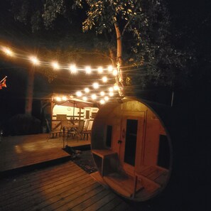 A cozy outdoor seating area with a wooden deck, a small table, and chairs under string lights.
