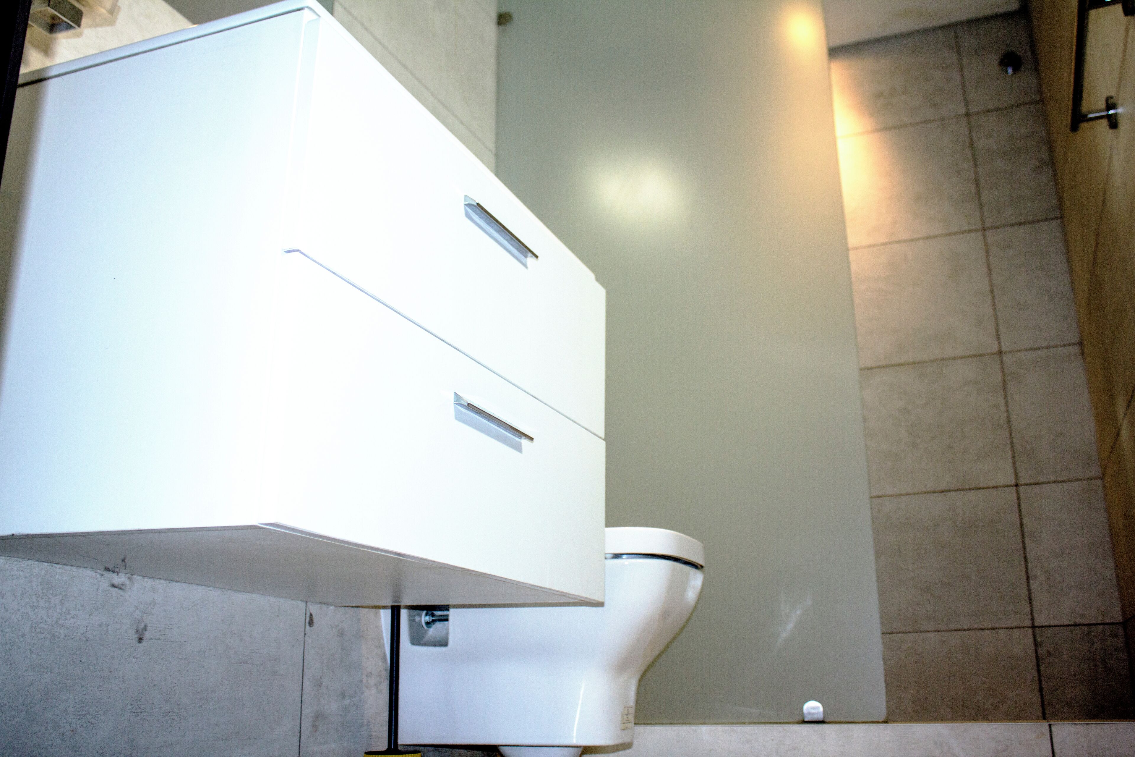 A bathroom with a white cabinet, a toilet, and tiled walls.