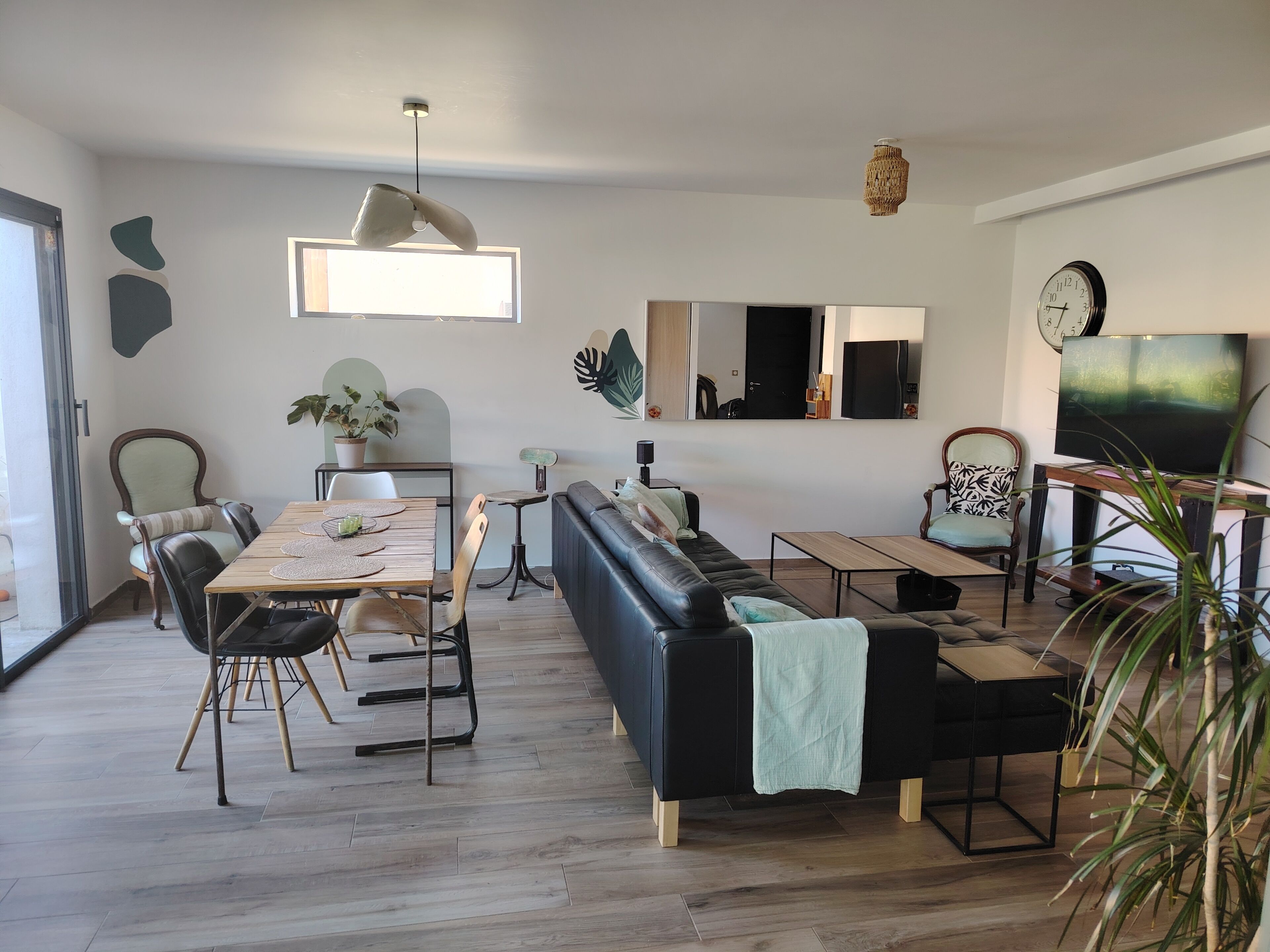 Ein modernes Wohnzimmer mit Esstisch, Sofa und Fernseher.