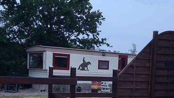 Una casa móvil con un mural de silueta de caballo, una puerta roja y una zona cercada.