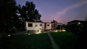 Een klein, gelijkvloers huis met een schoorsteen, een klein terras en een omheinde tuin.