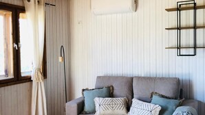 Una habitación acogedora con un sofá gris, una mesa de centro de madera y una ventana con cortinas.