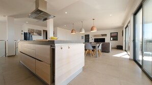 Une cuisine moderne dotée d’un îlot central, de luminaires suspendus et d’un coin repas avec des chaises et une table.