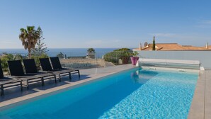 Une piscine sur le toit, avec une eau d’un bleu cristallin, des chaises longues et une vue sur l’océan.