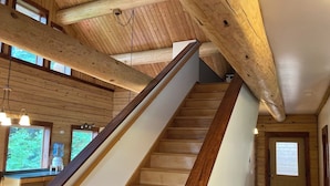 A wooden staircase with a handrail, a kitchen area with a water dispenser, and a door with a window.