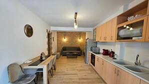 A modern kitchen with wooden cabinets, a dining area with a table and chairs, and a built-in oven. - Honeywell Comfort Stay (Markopoulo Mesogaias)