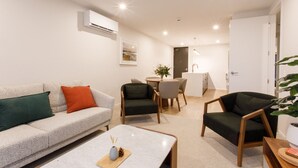 A modern living room with a sofa, chairs, a coffee table, and a dining area with a table and chairs. - Apartment with style (Wanaka)