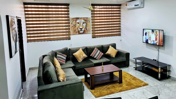 A modern living room with a sectional sofa, a coffee table, and a flat-screen TV. - Gorgeous Quiet & Comfy Close to Highway (Adentan)
