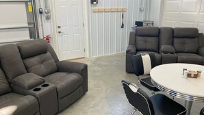 A modern living room with a gray sectional sofa, a black and white recliner, and a round table with two black chairs. - Newly built in Devils Lake, Perfect for Fishing or Relaxing.   (Devils Lake)