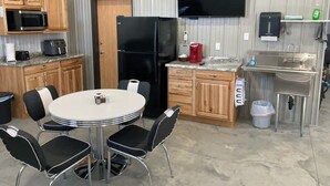 A compact kitchen with a microwave, refrigerator, and a flat-screen TV. There is a round table with chairs and a sink with a soap dispenser. - Newly built in Devils Lake, Perfect for Fishing or Relaxing.   (Devils Lake)