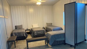 A compact room with four beds, a bench, a ceiling fan, and a large cabinet. - Newly built in Devils Lake, Perfect for Fishing or Relaxing.   (Devils Lake)