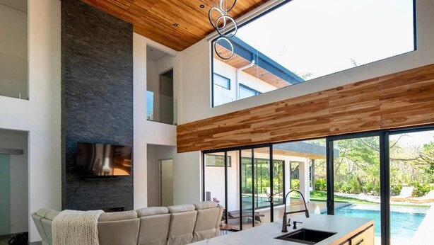 A modern kitchen with a large island, a built-in oven, and a view of a swimming pool. - La Ola Perfecta - Las Golondrinas Hacienda Pinilla (Hacienda Pinilla)