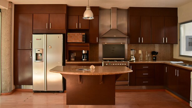 Una cocina moderna con armarios de madera oscura, electrodomésticos de acero inoxidable y una isla central.