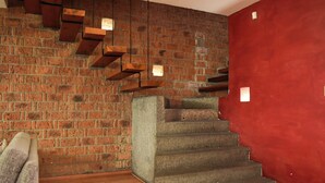 Una escalera con un muro de ladrillo y una pared de acento roja, escalones de madera y un banco acolchado.