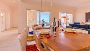 Un espace repas moderne avec une table en bois dressée pour un repas, de grandes fenêtres offrant une vue et un canapé bleu en arrière-plan.