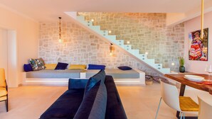 Un salon moderne avec un mur en pierre, un escalier, un canapé et un coin repas.