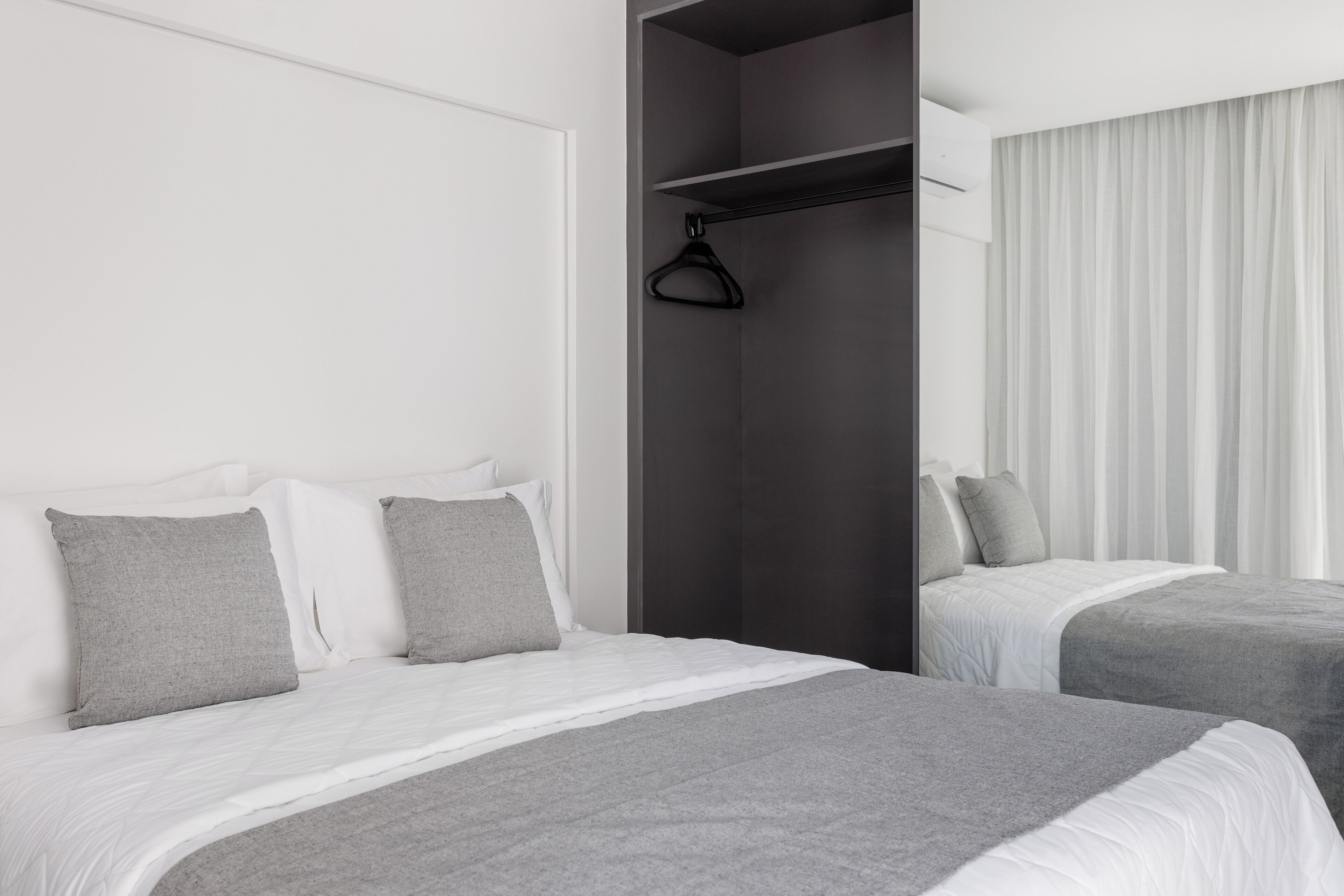 A hotel room with two beds, a wardrobe, and a hanging closet.