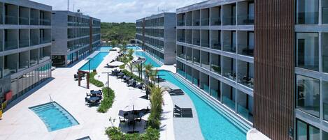 Un hotel moderno con piscina en la azotea, asientos al aire libre y vistas al entorno verde.