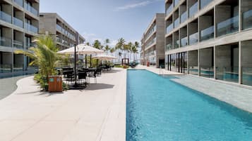 Un hotel moderno con piscina, asientos al aire libre y palmeras.