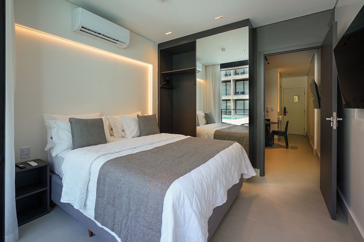 Une chambre à coucher moderne avec un grand lit, des tables de chevet, une armoire et un miroir.