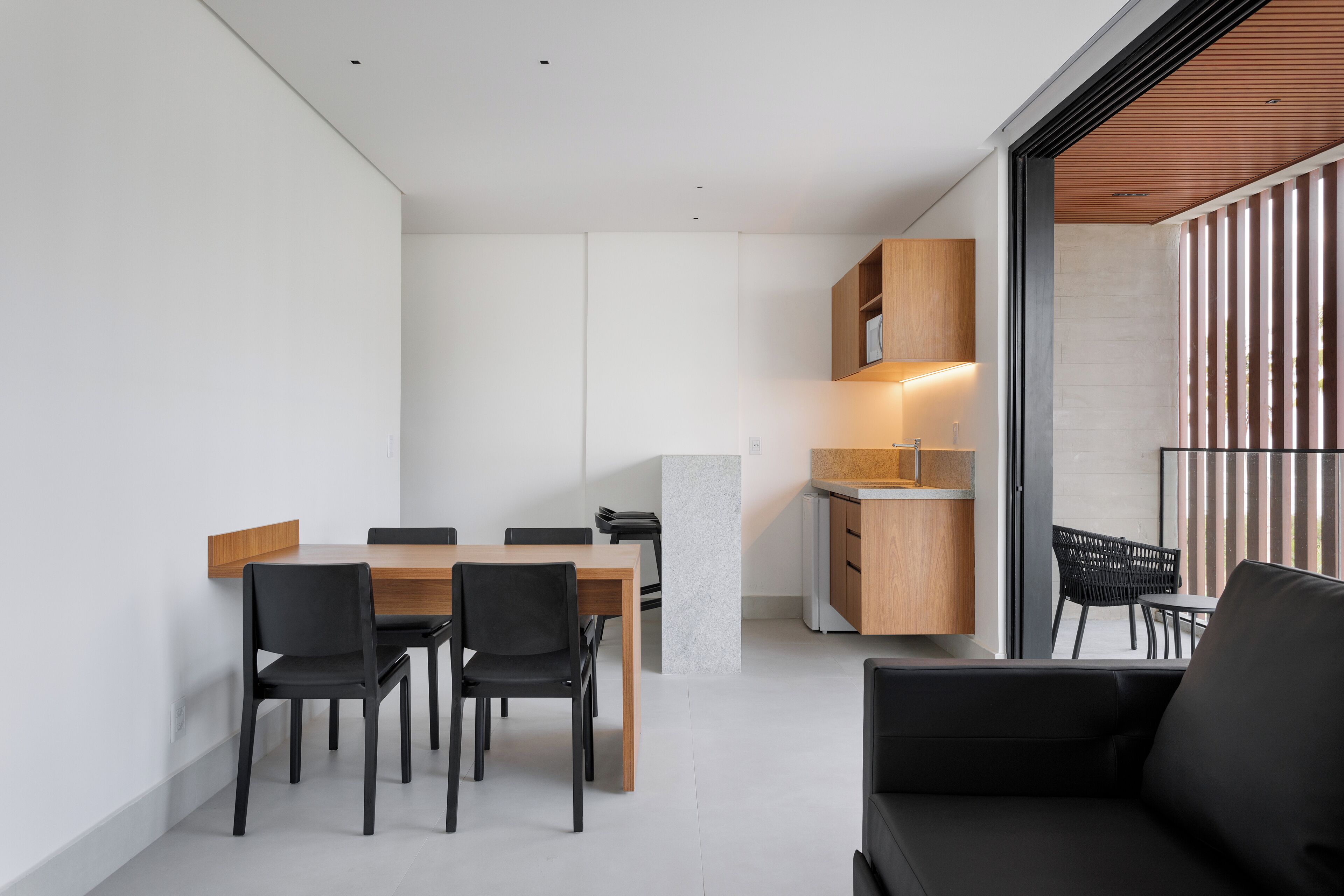 Een moderne keuken met een eethoek, met een houten tafel en stoelen, een inbouwoven en een groot raam met uitzicht.