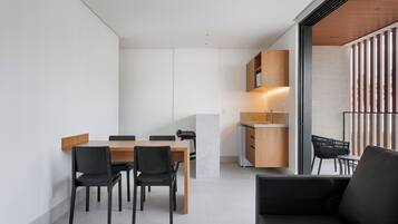 Een moderne keuken met een eethoek, met een houten tafel en stoelen, een inbouwoven en een groot raam met uitzicht.