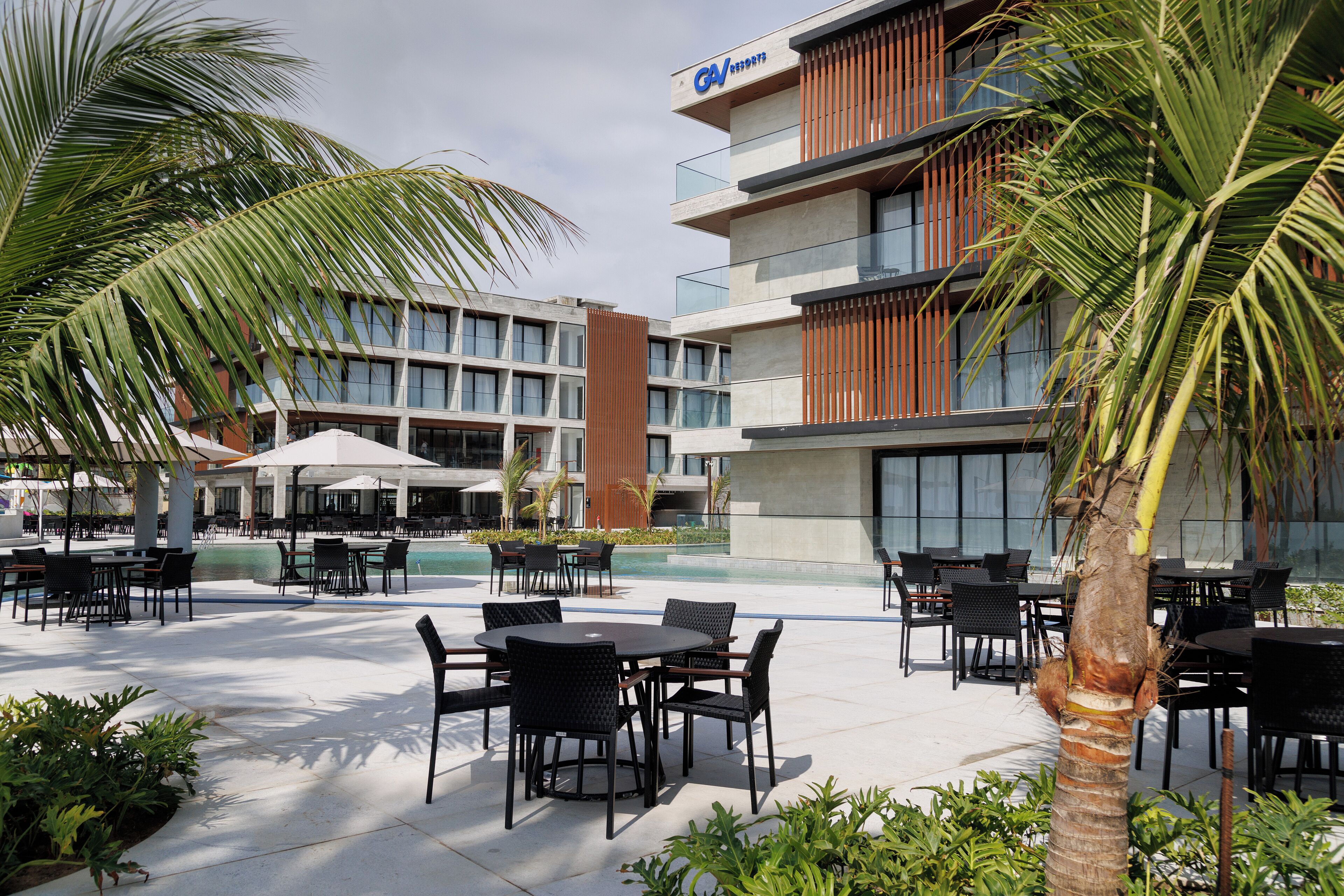 A hotel with outdoor seating, a pool, and modern architecture.