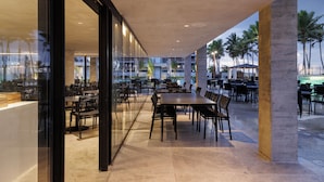 An indoor dining area with glass walls, tables, and chairs. - Porto Alto - GAV Hotéis e Resorts (Ipojuca)