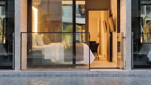 A modern hotel with a glass-enclosed bedroom, a pool, and a balcony with outdoor furniture. - Porto Alto - GAV Hotéis e Resorts (Ipojuca)