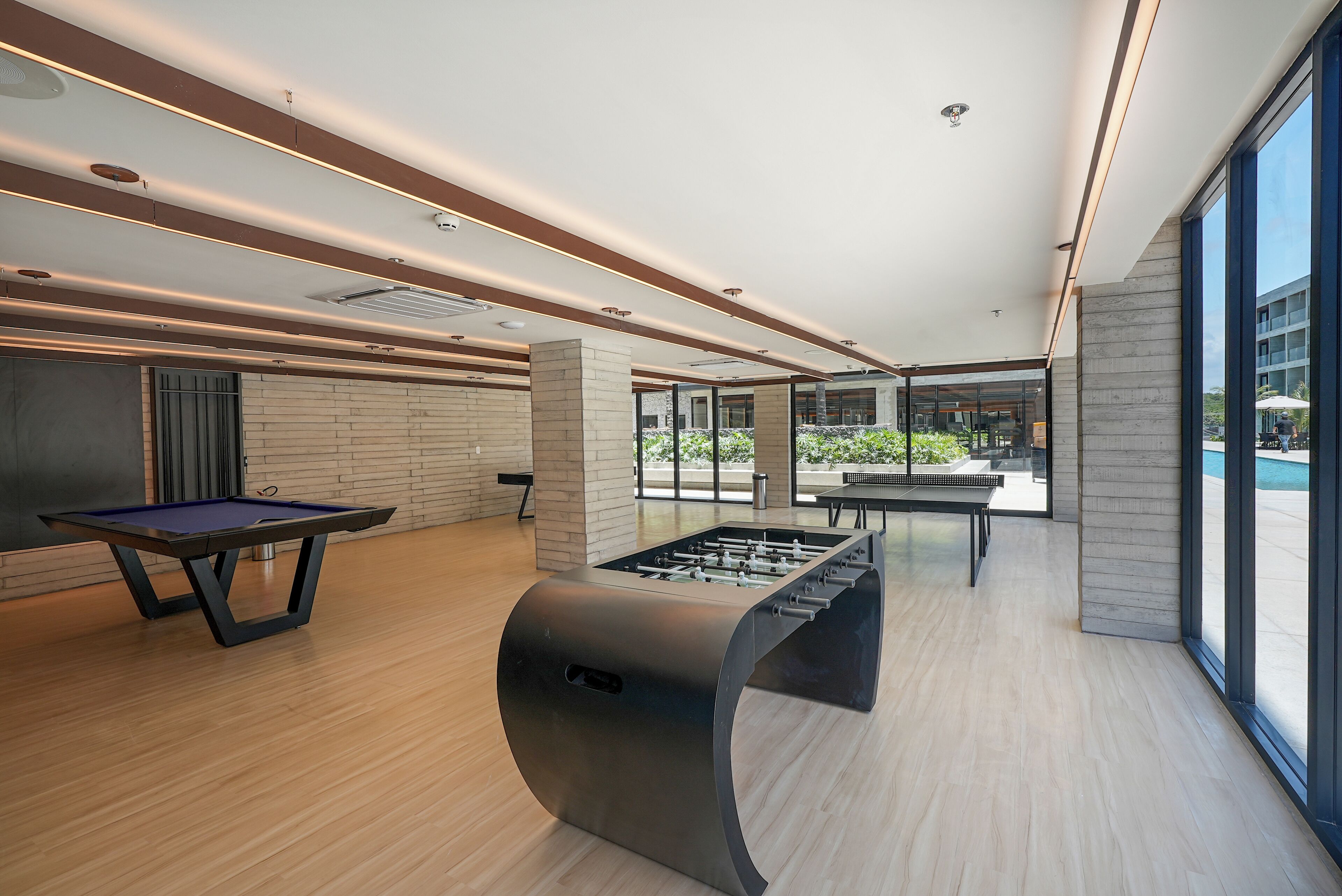 Uma área de lazer interna moderna com mesa de pebolim, mesa de bilhar e mesa de pebolim com design curvo exclusivo.