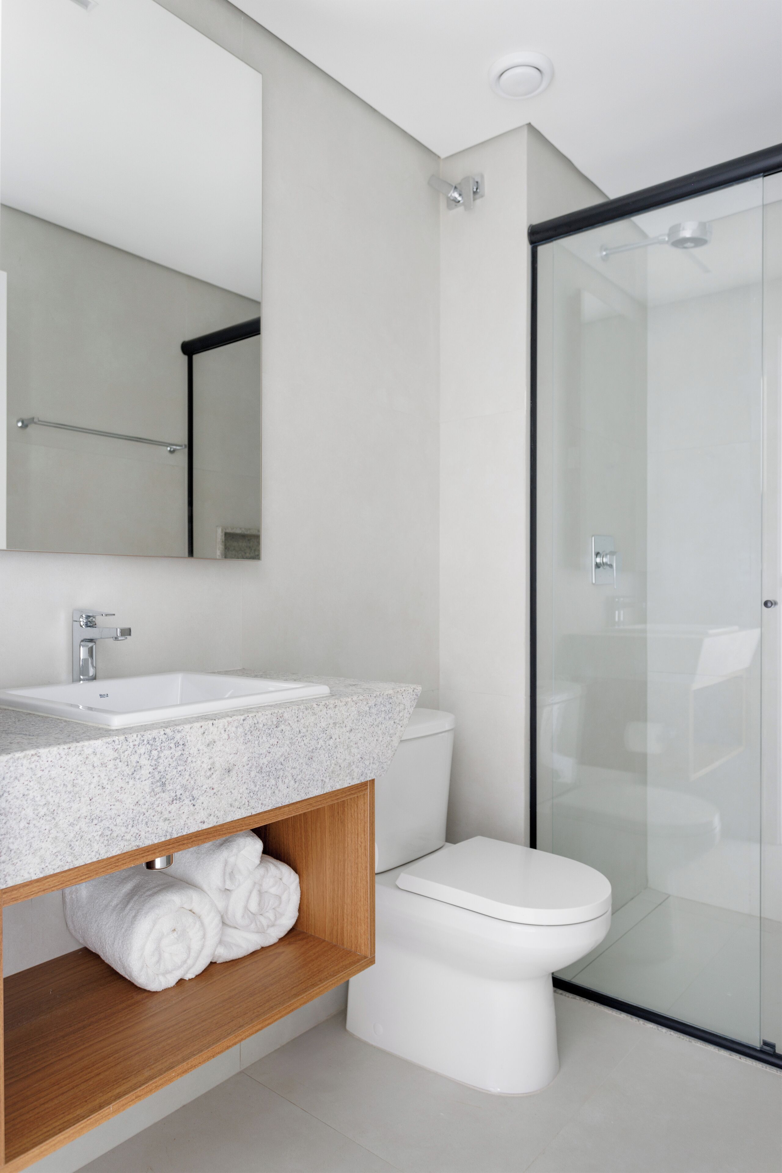 Un baño moderno con lavamanos blanco, inodoro y cabina de ducha de vidrio.