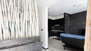 A modern interior with a stone wall, a black sofa, and a wooden sculpture. - Estudio en La Jaca, a 3 Minutos de la Playa, en un Lugar Ideal Para Desconectar (La Jaca)