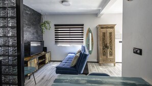 A modern living room with a blue sofa, a wooden cabinet, and a surfboard on the wall. - Estudio en La Jaca, a 3 Minutos de la Playa, en un Lugar Ideal Para Desconectar (La Jaca)