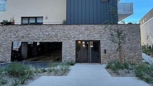 A modern building with a stone facade, a flat roof, and a large entrance with glass doors.