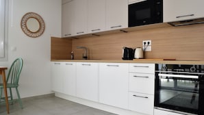 A modern kitchen with white cabinets, a black oven, and a wooden countertop.