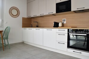 Eine moderne Küche mit weißen Schränken, einem schwarzen Backofen und einer Holzarbeitsplatte.