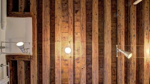 Habitación con paneles de madera en paredes y techo, dos lámparas colgantes y una barra para cortinas blanca.