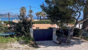 Une cour recouverte de gravier avec un trampoline, une porte et un arbre.