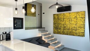 Une cuisine moderne dotée d’un plan de travail blanc, d’une machine à café intégrée et d’un escalier pourvu d’un système d’éclairage intégré.