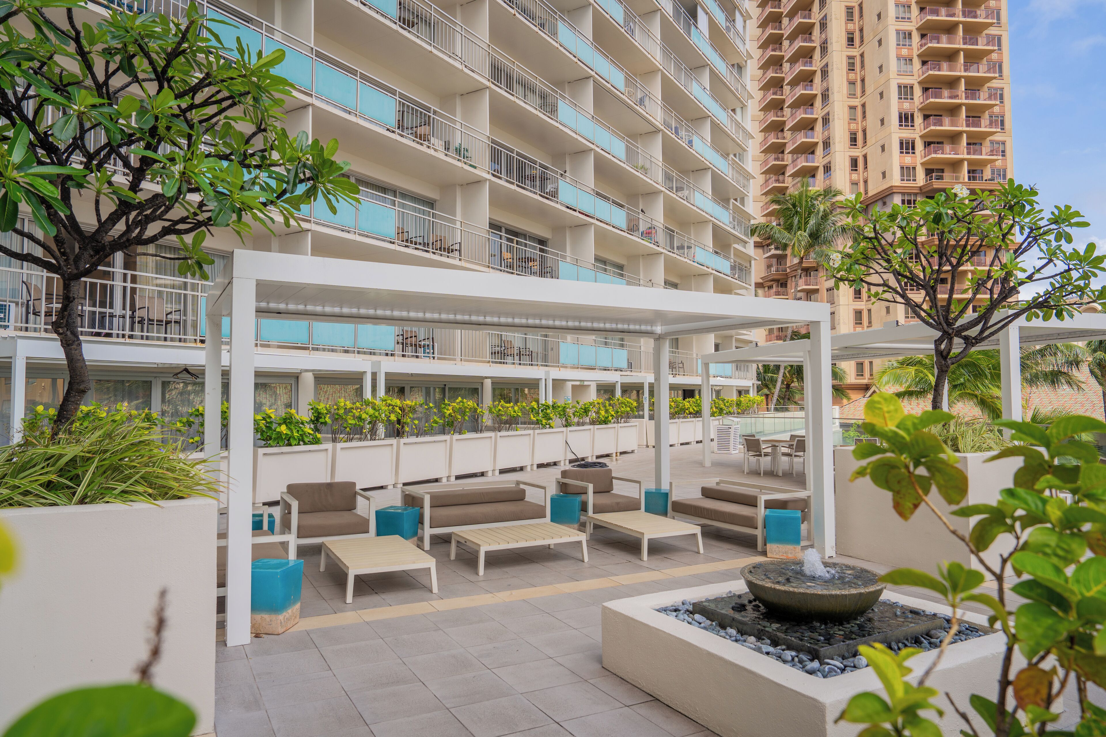 A rooftop lounge with outdoor seating, a fire feature, and a view of high-rise buildings.