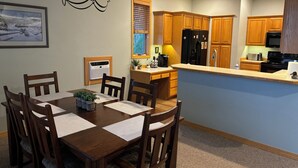 A modern kitchen with wooden cabinets, a black refrigerator, a stove, and a dining area with a wooden table and chairs. - Townhouse in beautiful North Helena Valley, below the majestic Sleeping Giant (Helena)