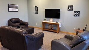 A living room with two leather sofas, a wooden coffee table, a flat-screen TV, decorative wall art, and a small potted plant. - Townhouse in beautiful North Helena Valley, below the majestic Sleeping Giant (Helena)