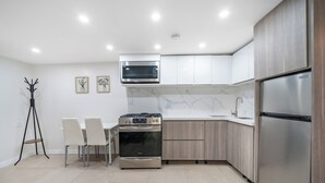 A modern kitchen with white cabinets, a stainless steel refrigerator, a microwave, and a gas stove. - 16 shower Head Stay Luxury Stay (Passaic)