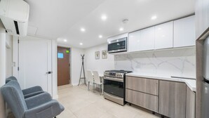 A modern kitchen with white cabinets, a built-in microwave, a stove, and a refrigerator. - 16 shower Head Stay Luxury Stay (Passaic)