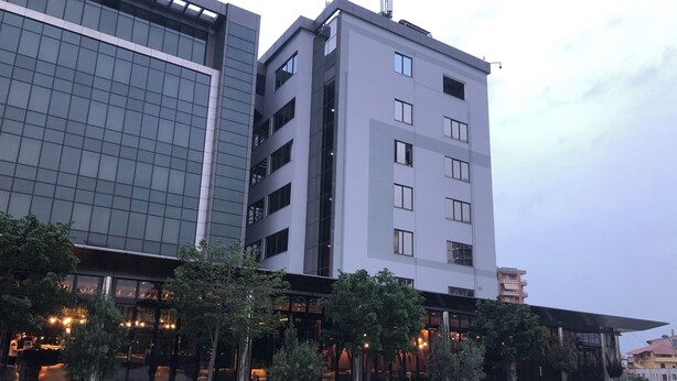 A modern building with multiple floors, large windows, and a well-maintained lawn with trees.