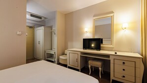 A hotel room with a bed, a desk with a television, a mirror, and a wardrobe. - Riverside rooms at Hotel Fieri (Fier)